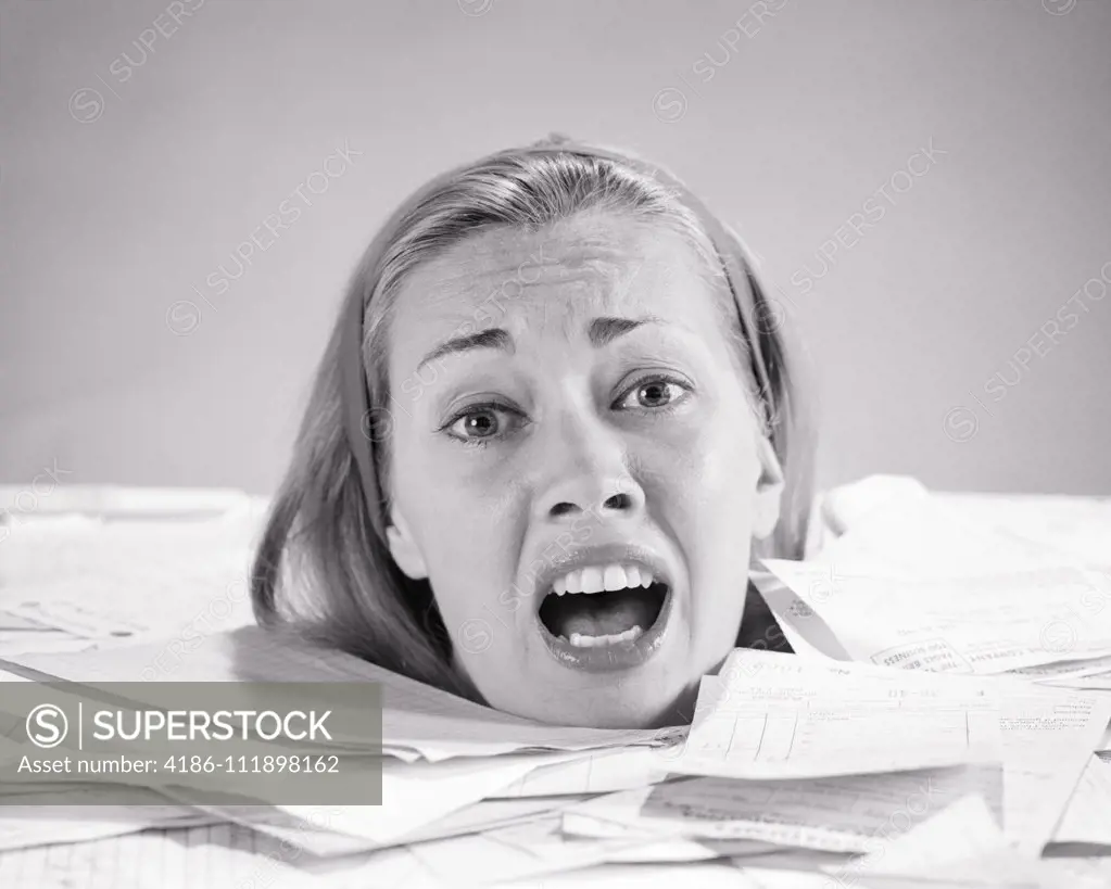 1960s WOMAN UP TO  HER NECK DROWNING IN PAPER BILLS INVOICES SHOUTING FOR HELP LOOKING AT CAMERA