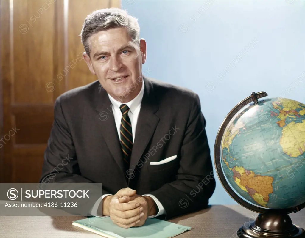 1960S Portrait Man Businessman Sitting At Desk Next To Globe Of The Earth  
