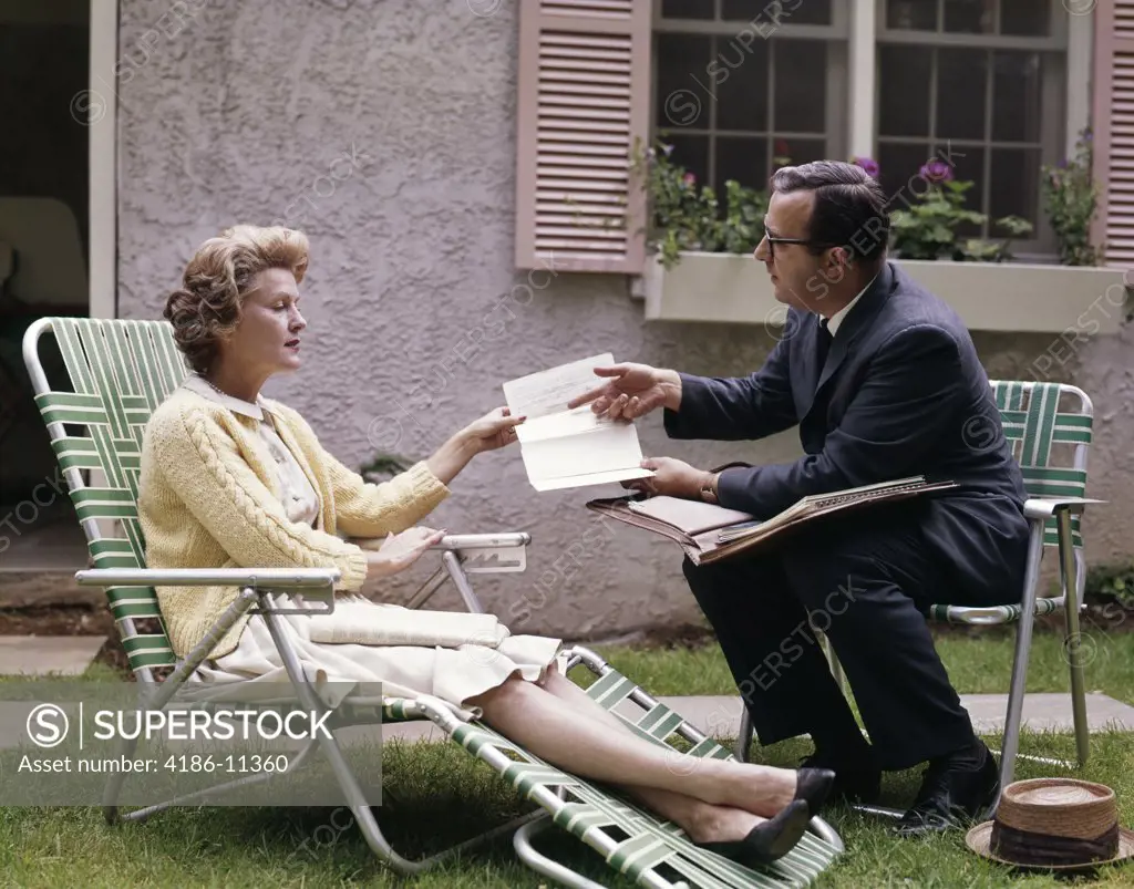 1960S Man Showing Material In Papers To Woman Sitting Outside Suburban House Insurance Medical Salesman