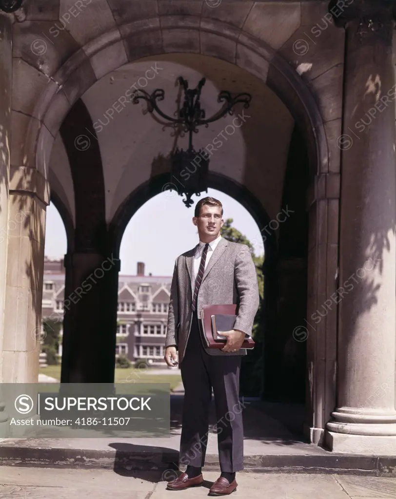 1960S Man College Student Standing Near Arch Leading To College Campus Quadrangle