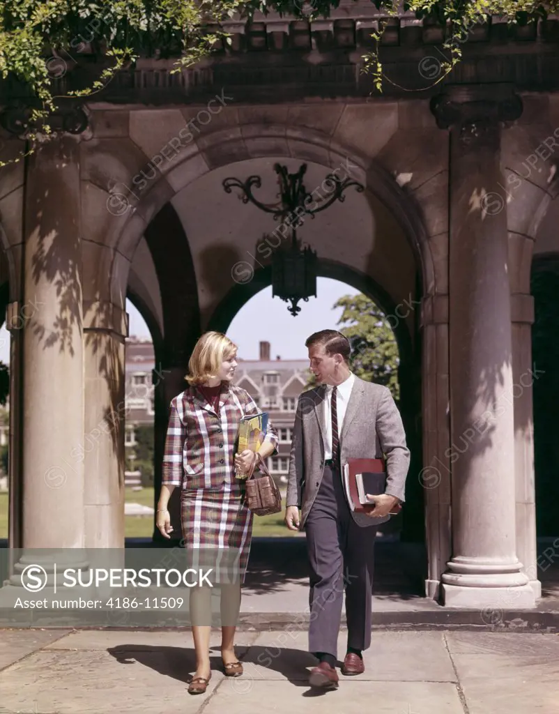 1960S Man And Woman Students With Books At Arch Leading To Campus Quadrangle Couple Two