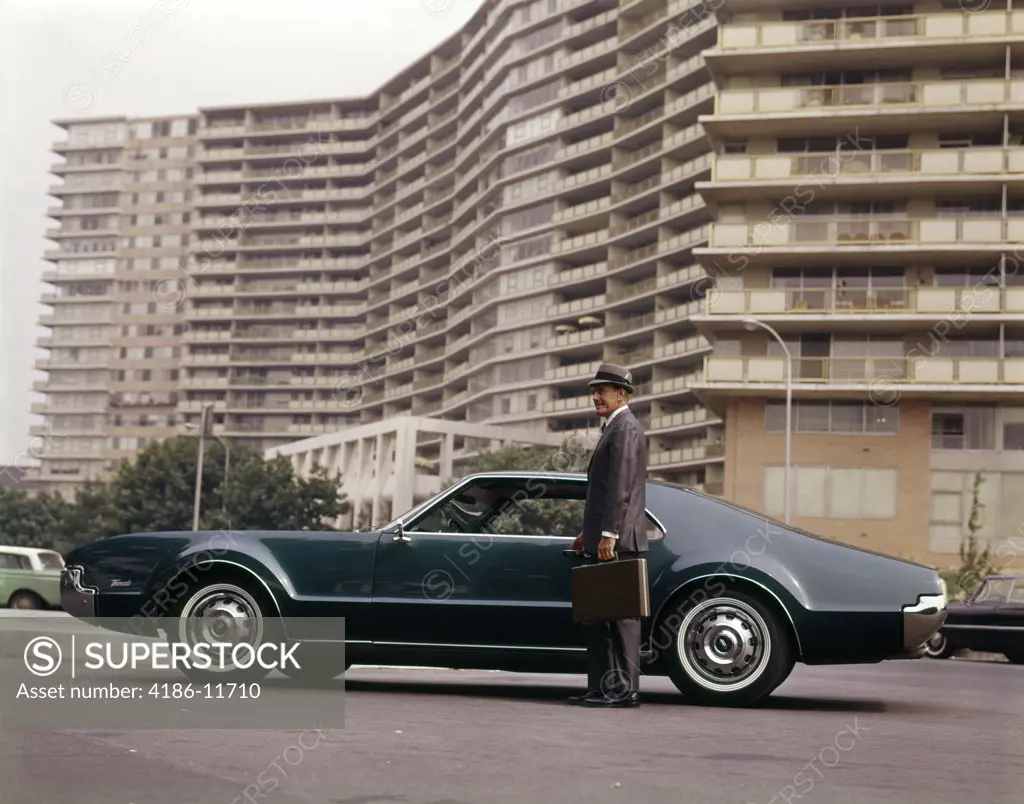 1970S Salesman With Attaché Case Standing Beside Car Outside Apartment Condominium Building