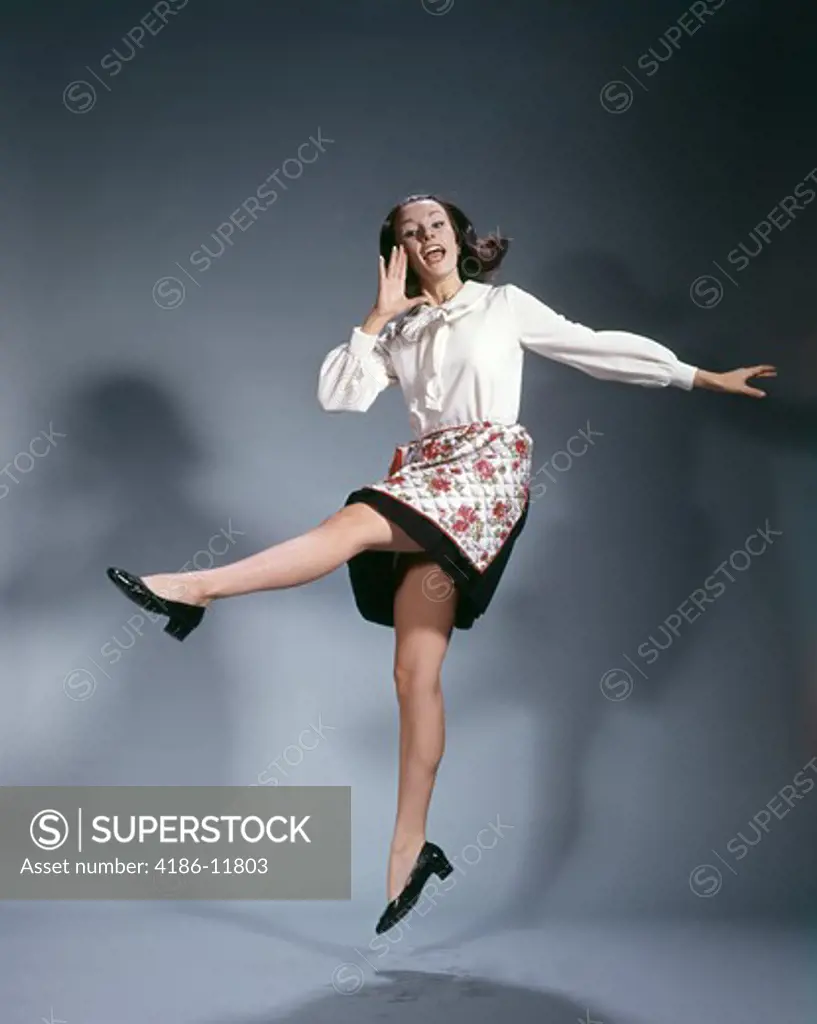 1960S Young Woman Wearing Apron Jumping Into The Air And Shouting Happy Symbolic Kicking Joy Triumph