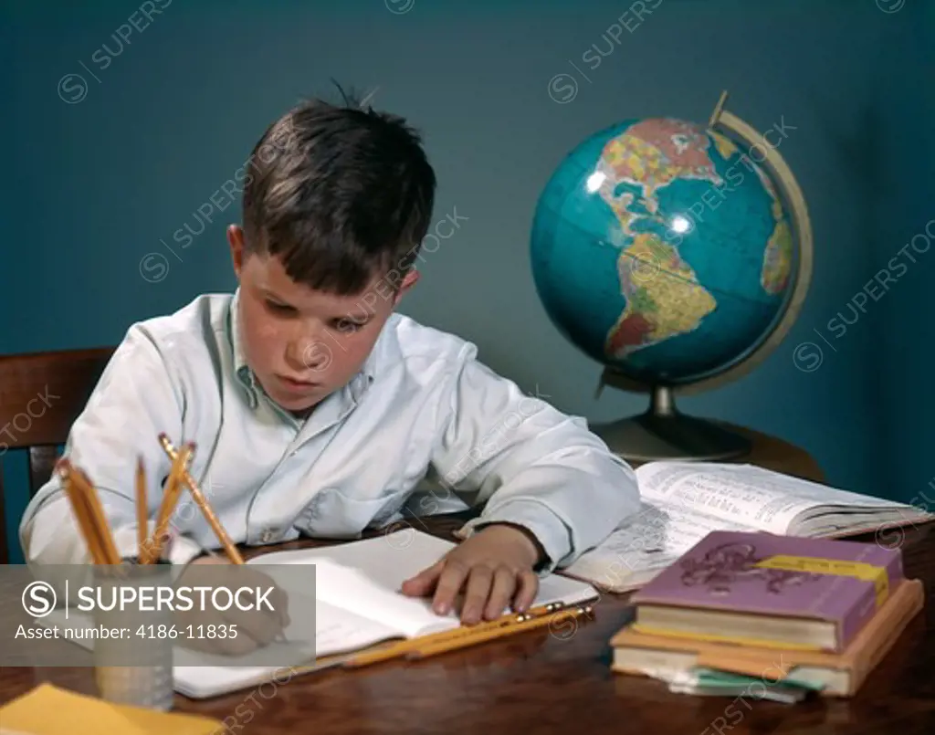 1960S 1970S Boy Doing Homework At Desk Writing Notebook Books Globe
