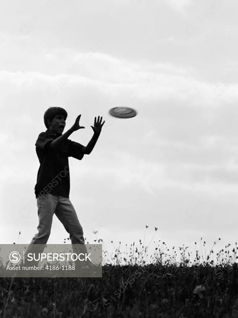 1960S 1970S Silhouette Of Boy Catching Frisbee In Field