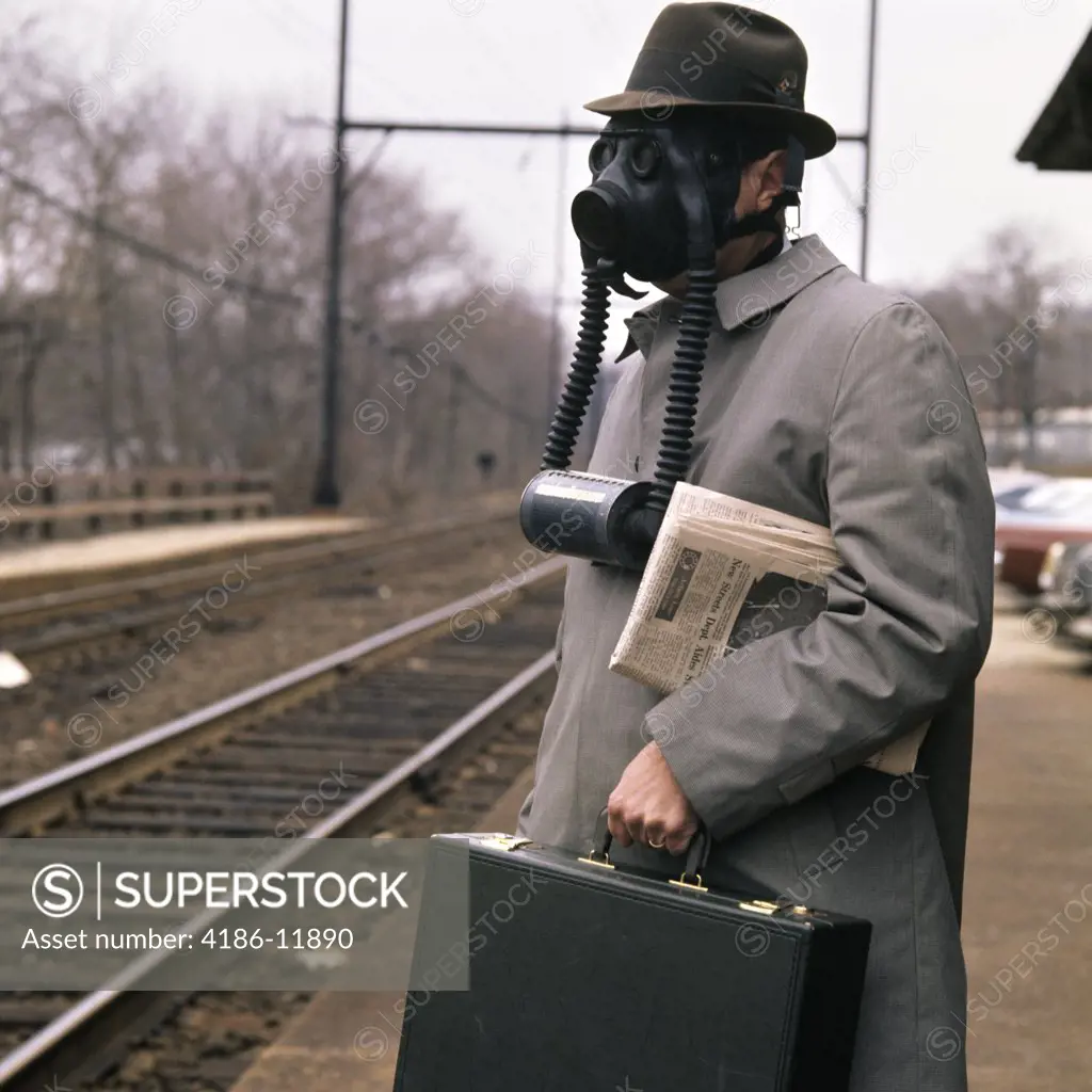 1960S Man Businessman Commuter Wearing Gas Mask For Pollution Waiting For Train