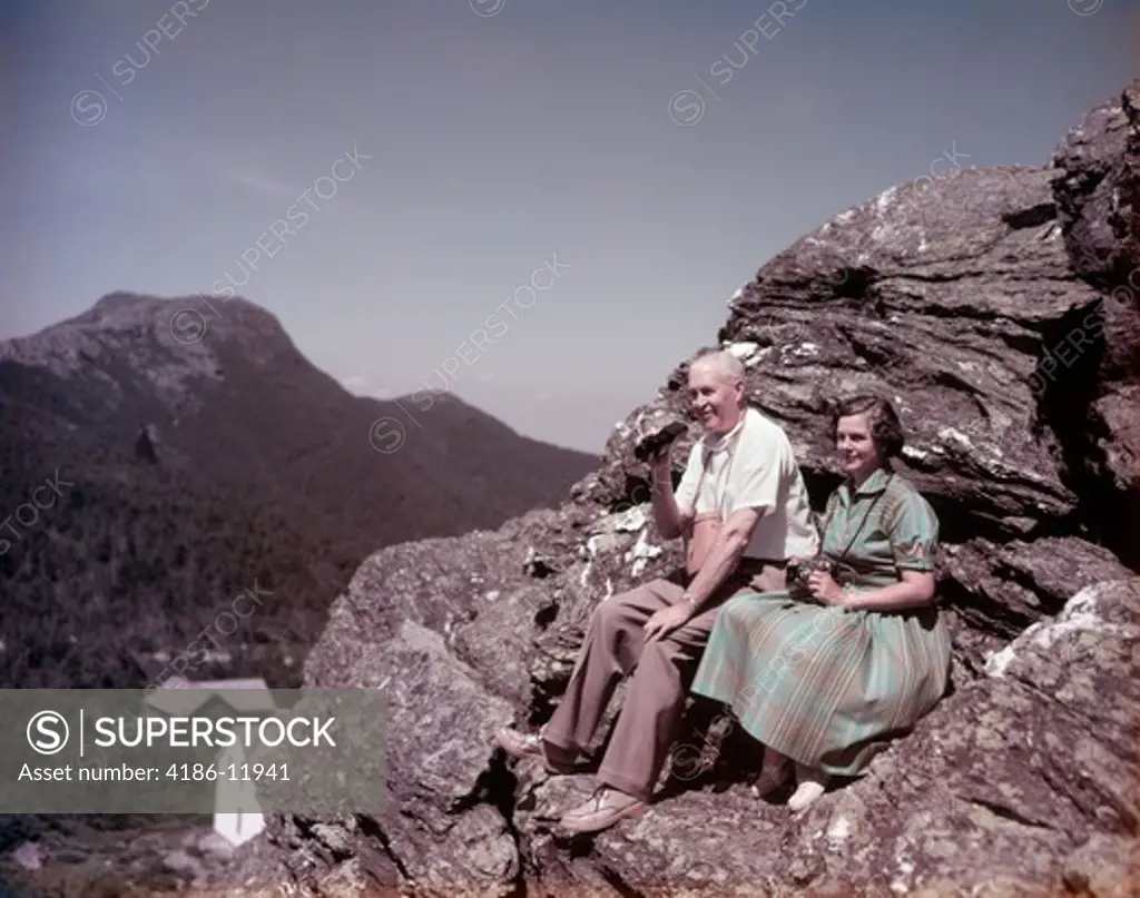 1950S Senior Couple On Rocks Top Of Mount Mansfield Vt Man Has Binoculars Woman In Green Dress Camera On Neck Retire Travel