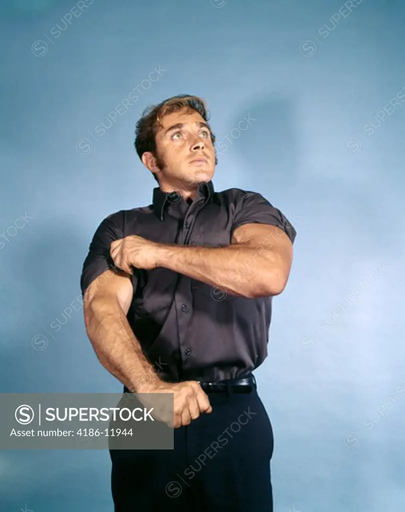 1970S Muscular Young Man Rolling Up Shirt Sleeve Symbolic Ready To Work Intent Determined