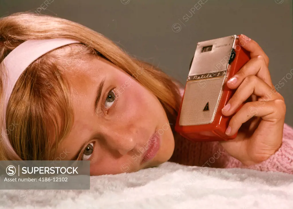 1950S 1960S Teenage Girl Holding Red Silver Small Transistor Radio To Her Ear Listening