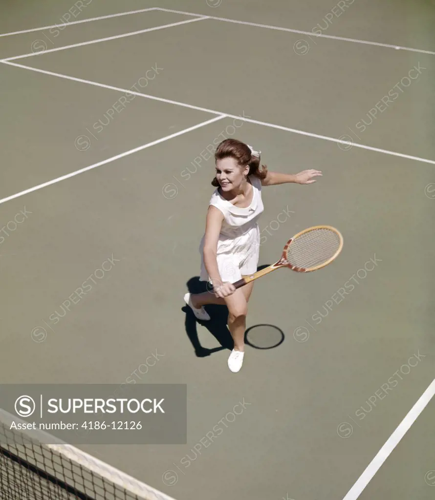 1960S Smiling Woman Playing Tennis Swinging Wood Racket To Hit Ball