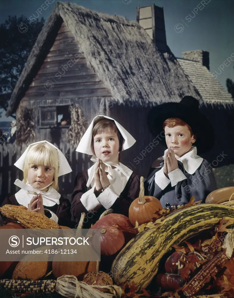 1960S Three Children Wearing Pilgrim Outfits And Saying Grace Backdrop Of Plymouth Plantation