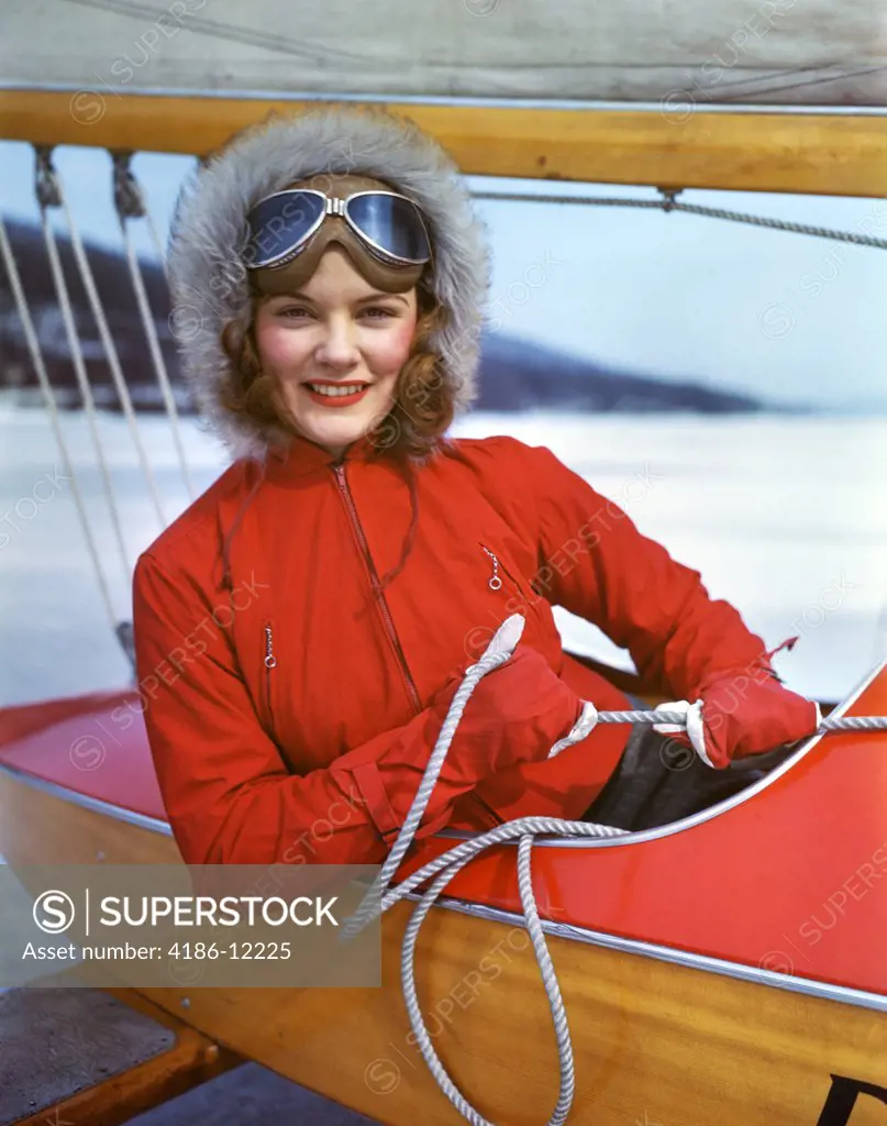 1940S Smiling Young Woman Wearing Gloves Fur Hat Goggles Sitting In Cockpit Of Ice Boat Holding Sheet Rope To Sail Boom