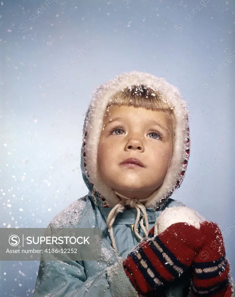 1960S Little Girl Holding Snow Ball Looking Sad Up At The Sky Red Mittens White Knit Hat Blue Jacket