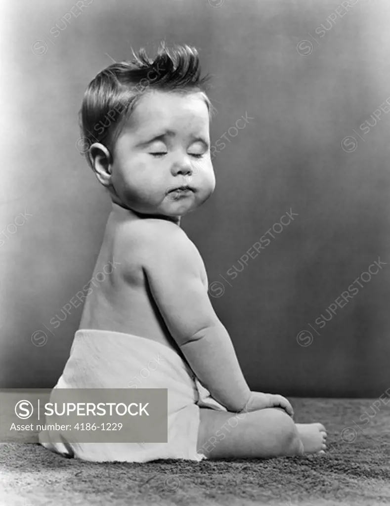 1940S 1950S Baby Seated With Back To Camera Turning Head To Viewer With Eyes Closed