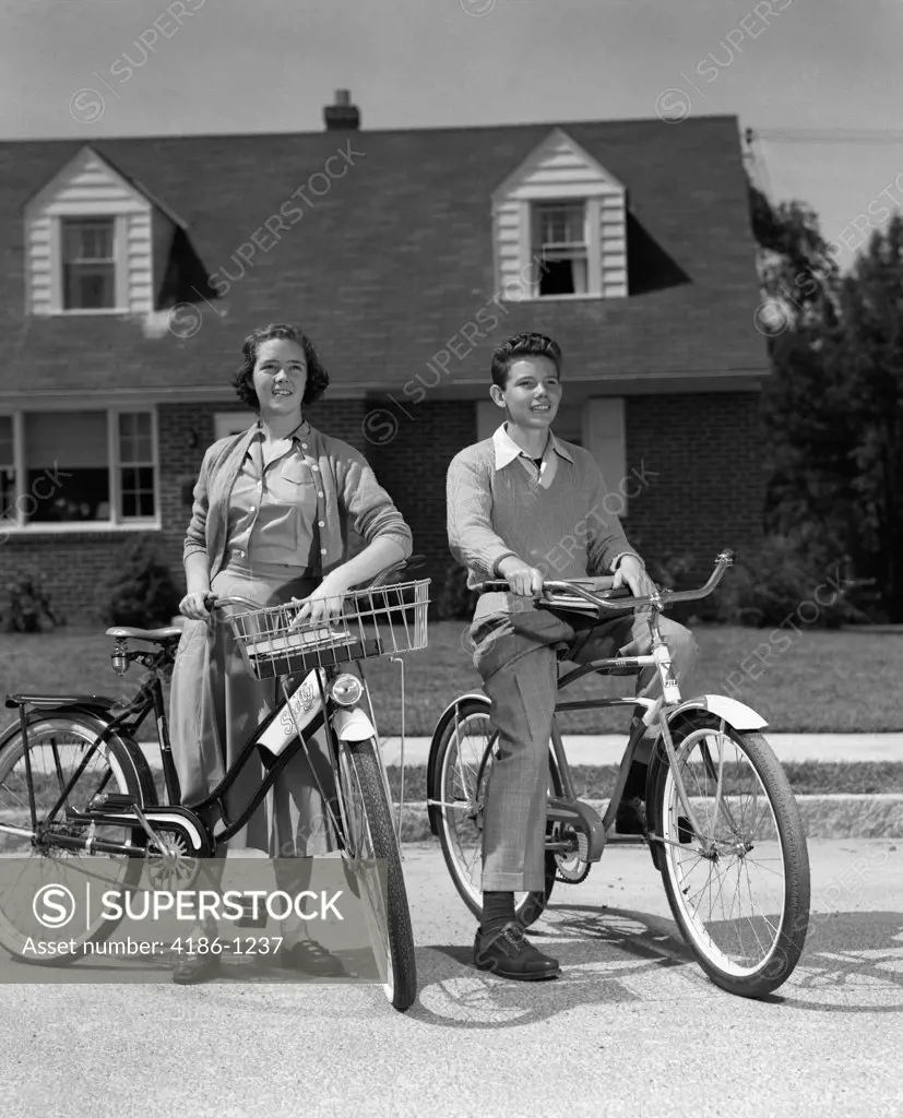 1950S Smiling Teens On Suburban Street Boy Sitting On Bike Girl Standing Beside Bike With Basket
