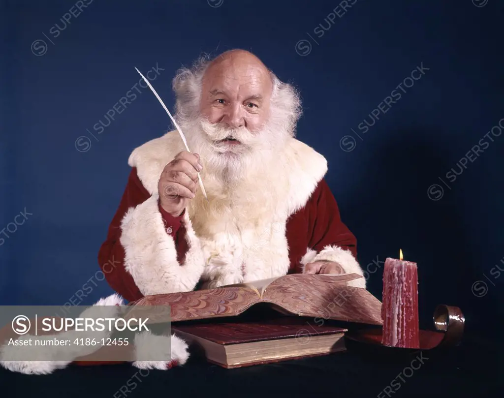 1960S Santa Sitting At Desk With Open Book Making A List With Quill Pen