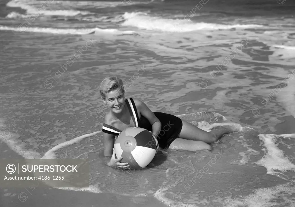 1960S Woman In Bathing Suit Lying In The Surf Holding A Beach Ball Smiling Outdoor