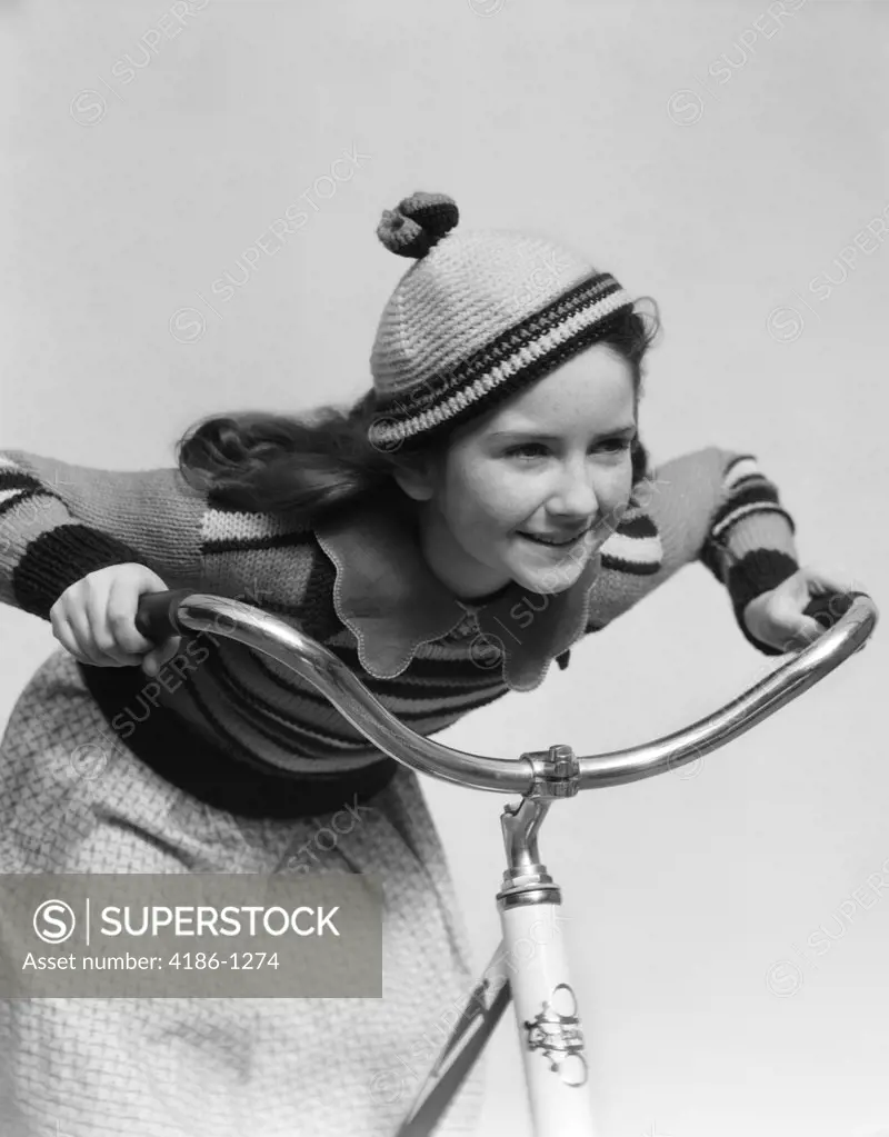 1930S Smiling Eager Little Girl In Knit Cap And Matching Sweater Riding Bike Leaning Into Handlebars