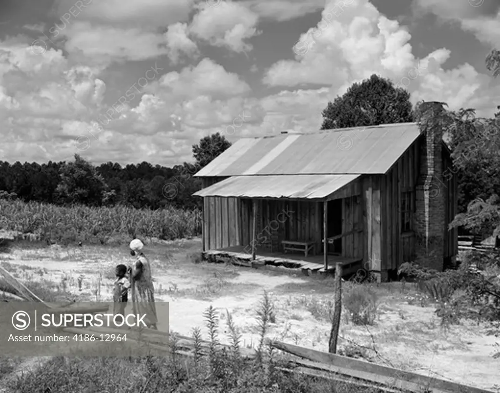 1960S Simple Wooden House African American Woman And Boy Looking In The Distance At Farm Near Greenville Alabama Summer Outdoor