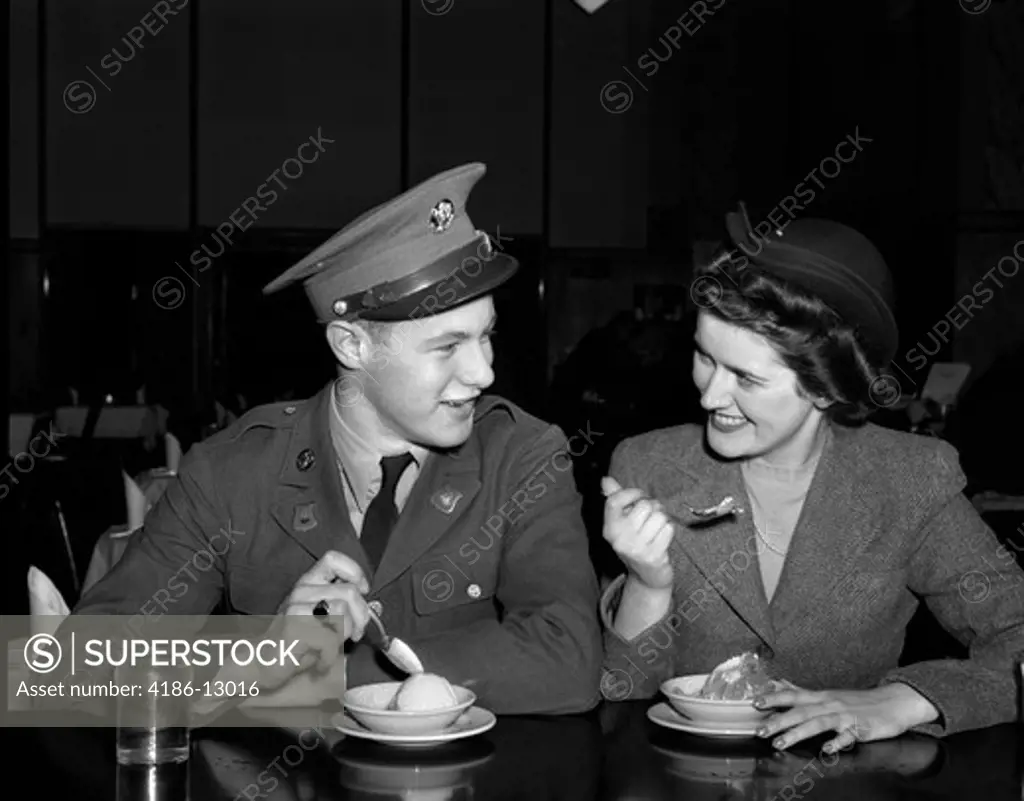 1940S Smiling Couple Man Soldier In Army Uniform And Woman Girlfriend Sitting At Soda Fountain Counter Eating Dish Of Ice Cream