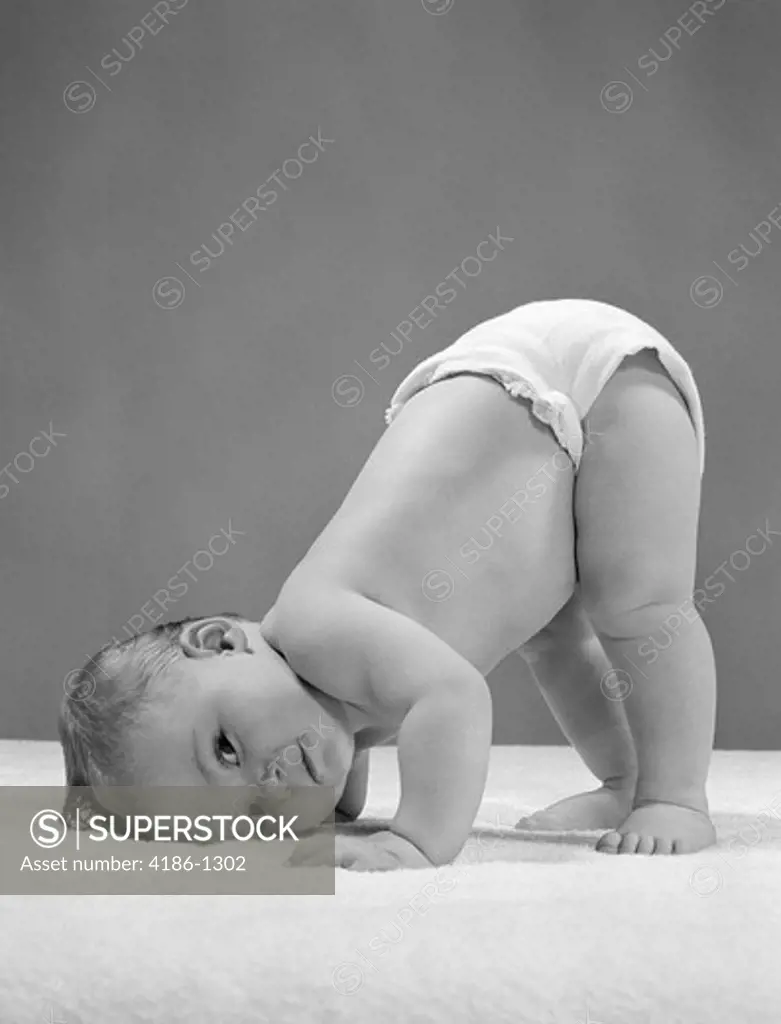 1950S Side View Of Portrait Baby In Diaper With Cheek To Floor And Bottom In Air