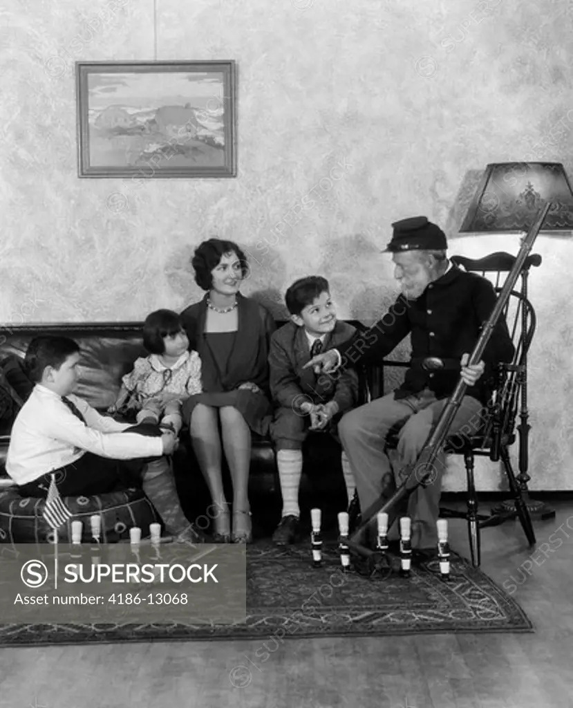 1920S 1930S Mother And Three Children Listening To Grandfather In Civil War Union Uniform Holding Rifle Tell Stories