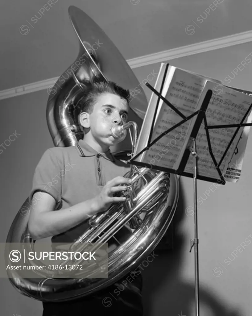 1960S Boy Playing The Tuba While Reading From Sheet Music On A Music Stand Inside