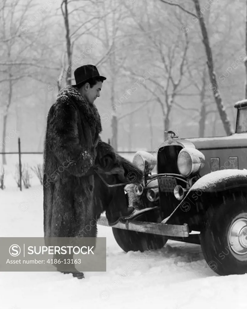 1930S Man In Hat And Raccoon Fur Coat Standing Foot On Bumper Of Chevrolet Roadster Stalled In Snow Storm