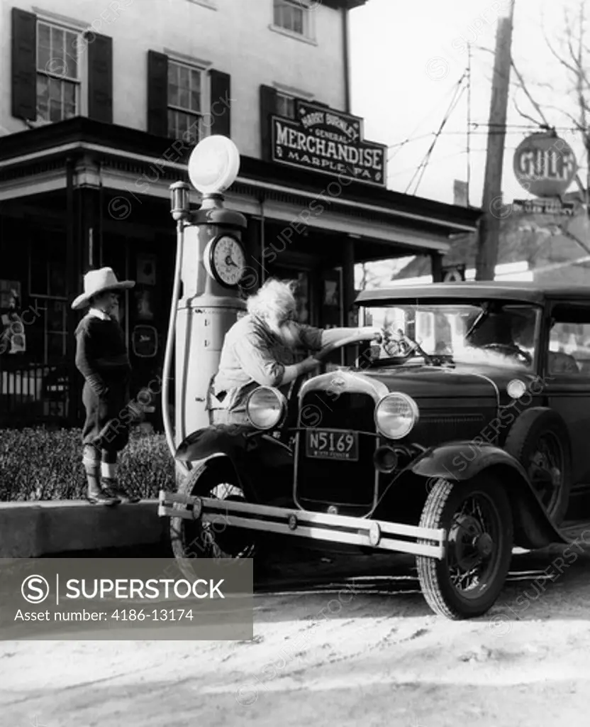 Elderly Grandfather Filling Up Ford Car In Front Of Pennsylvania General Store With Grandson Watching 1930S