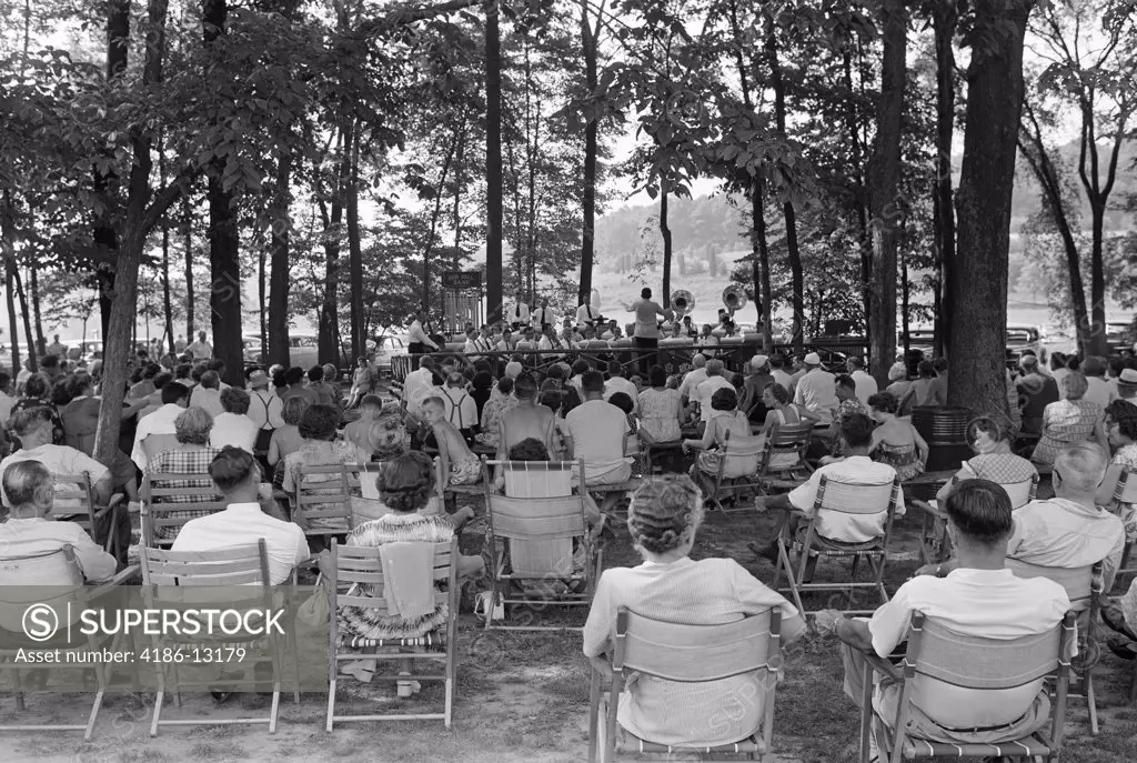 1950S Crowd Group Men Women Sit Folding Chairs Under Shade Trees Listening Summer Band Concert Small Town