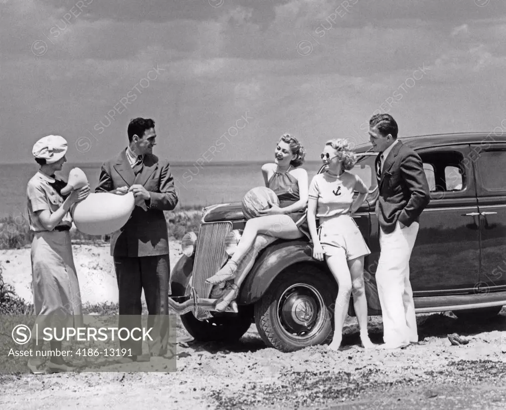 1930S Group Of Five Men & Women At 1936 Ford V-8 Parked Along Shore Playing With Inflatable Beach Toys