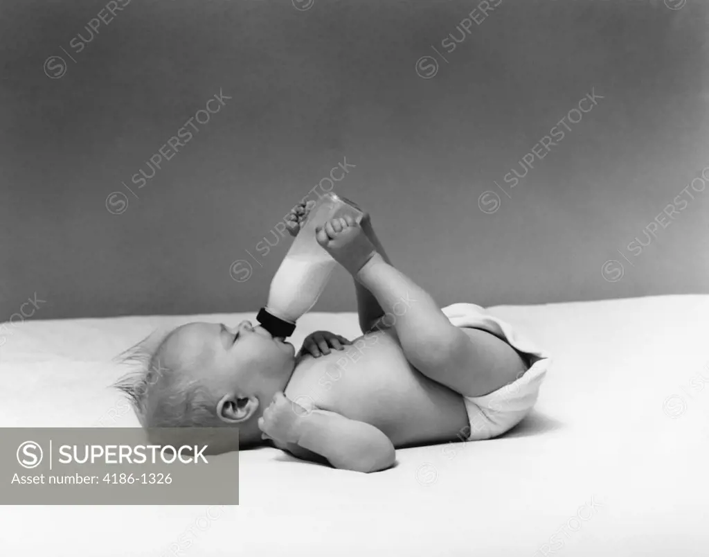 1940S Baby Prone Drinking From Milk Bottle Held With Feet