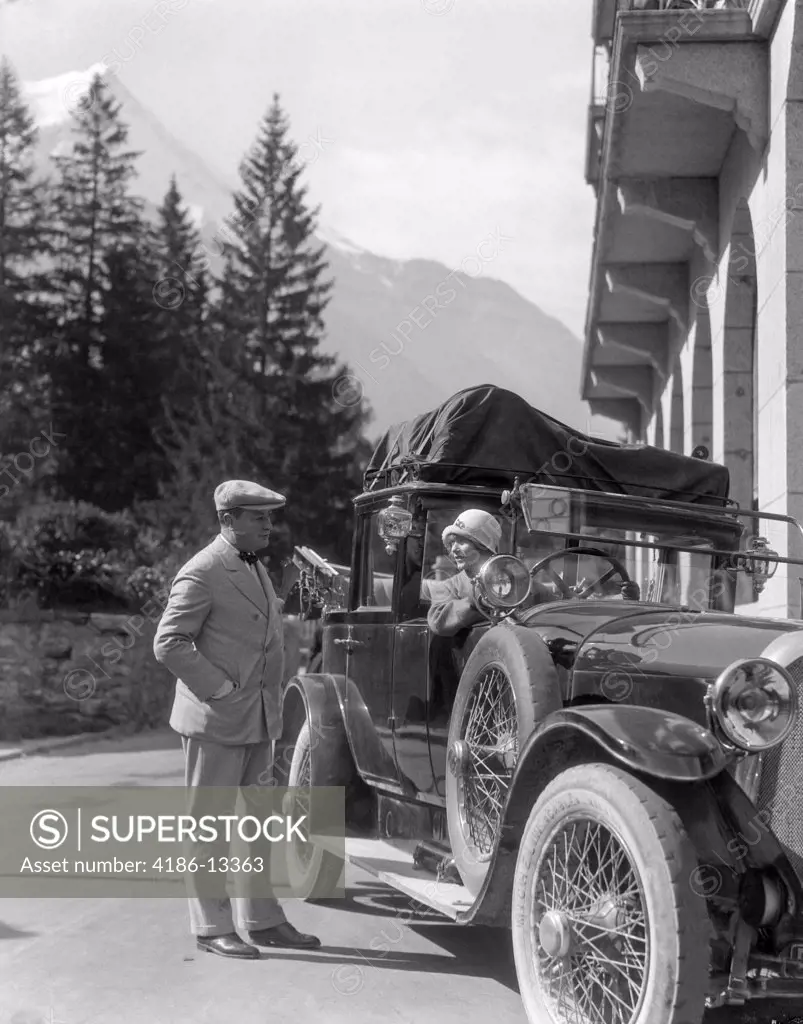 1920S Couple Man Standing Beside Car Woman Driving Roadster Touring Car Top Full Of Covered Luggage