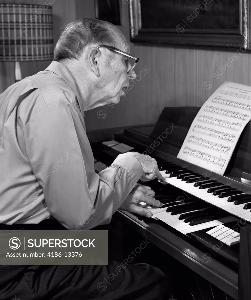 1970S Elderly Man Wearing Glasses Leaning Forward To Read Sheet Music While Playing Organ