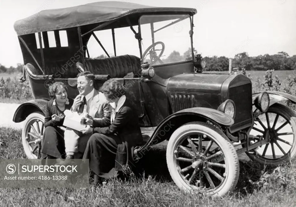 1920S Two Women & One Man Sitting On Running Board Of Model T Ford Eating Lunch Talking & Laughing