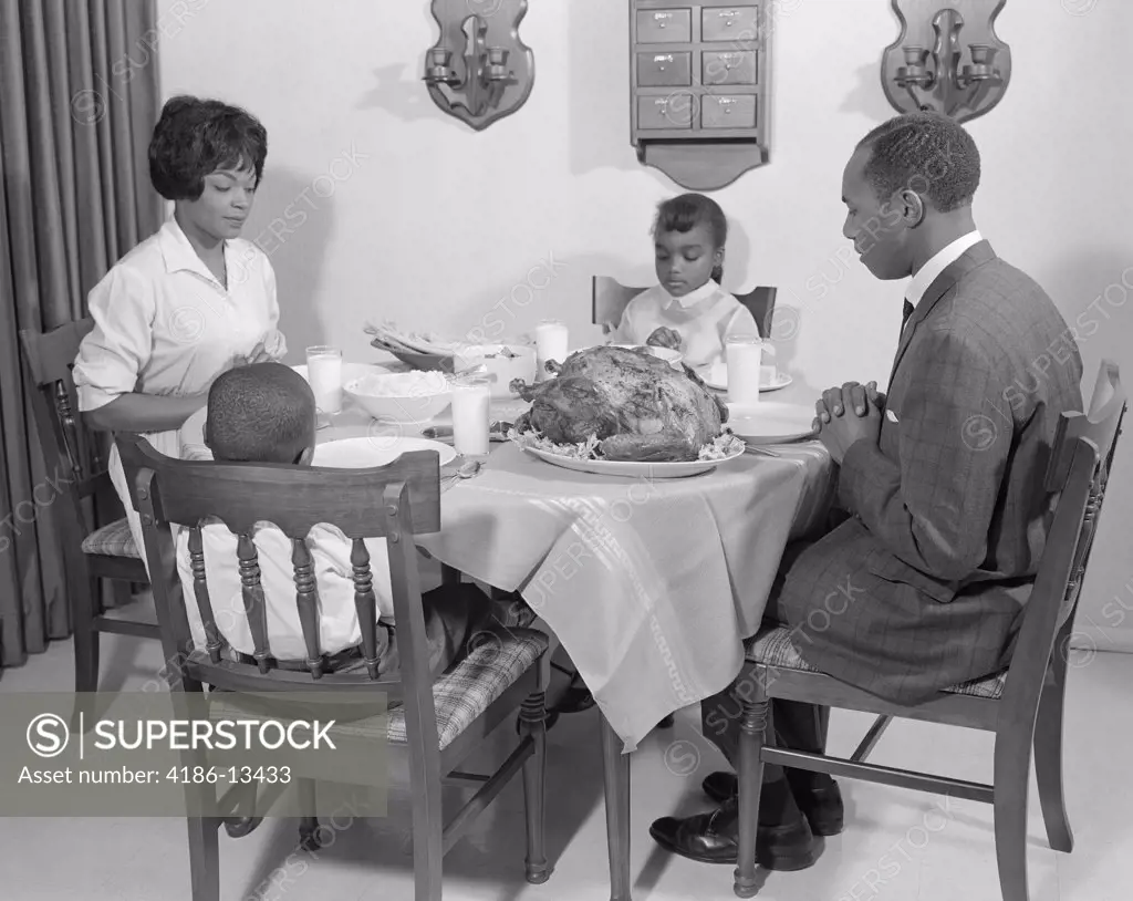 1960S African-American Family At Dining Table With Turkey Saying Grace Praying