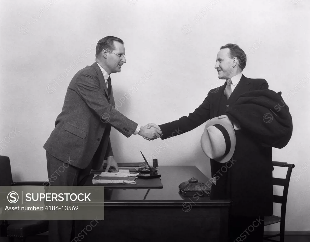 1930S Two Men Shaking Hands At Desk In Office