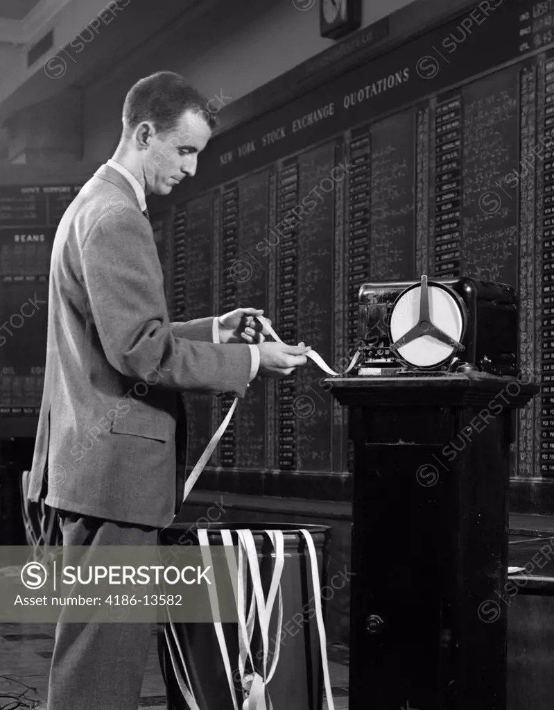 1950S 1960S Stockbroker Reading Ticker Tape In Front Of Stock Exchange Board