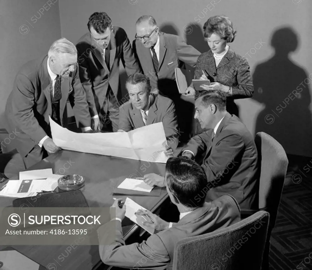 1950S 1960S Conference Room With Men Looking Over Papers While Secretary Takes Notes