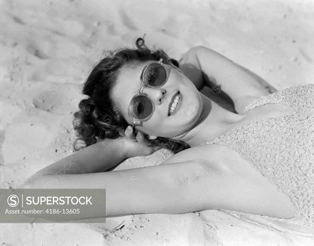 1930S Woman In Sunglasses Lying On Beach Wearing Bathing Suit