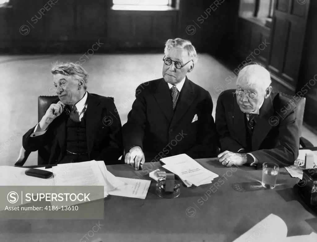 1930S 1940S Group Of Three Elderly Businessmen Sitting At Conference Table With Attention Directed To Speaker Not Shown