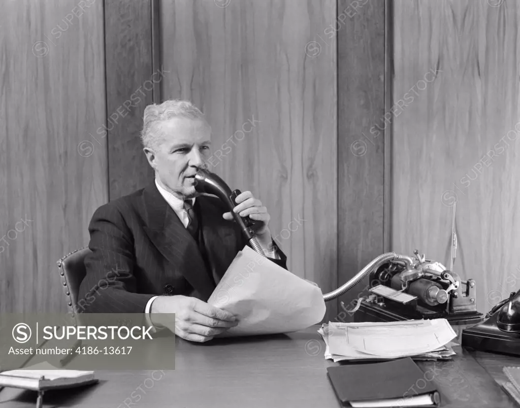 1930S Elderly Male Executive Sitting At Desk Speaking Into Dictaphone
