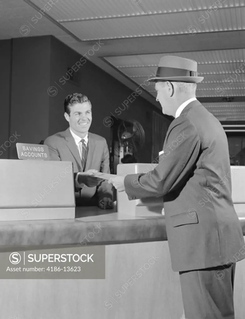 1960S Businessman Making A Deposit Into Savings Account With Bank Teller 