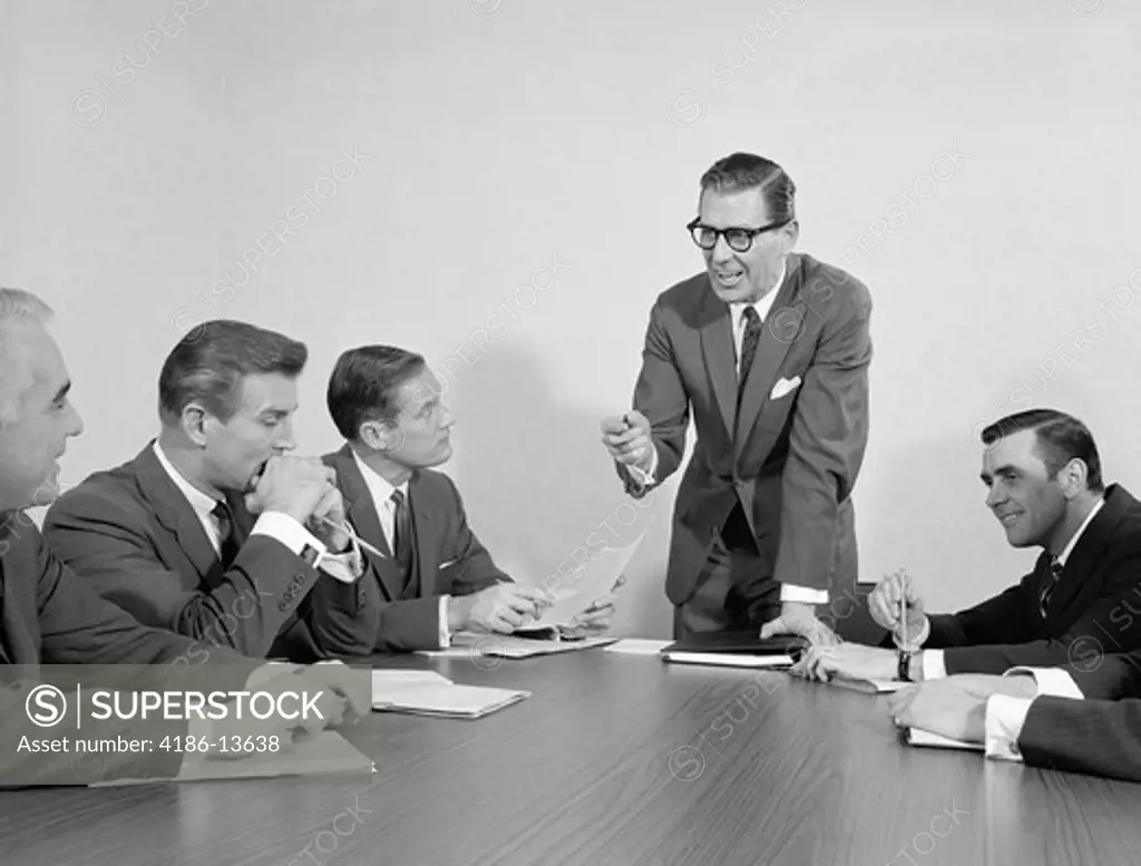 1960S 5 Executive Businessmen Meeting At Conference Table One Man Standing