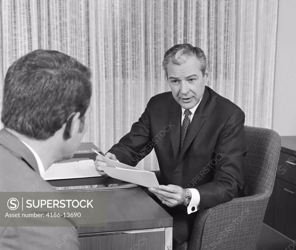 1960S 1970S Man From Behind Meeting At Desk Of Older Businessman  