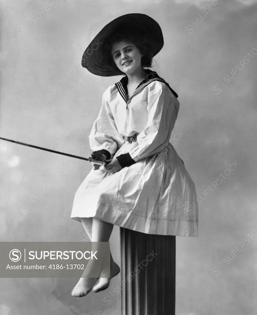 1910S 1920S Woman Wearing Dress With Sailor Style Collar Straw Hat Sitting On Post With Fishing Rod