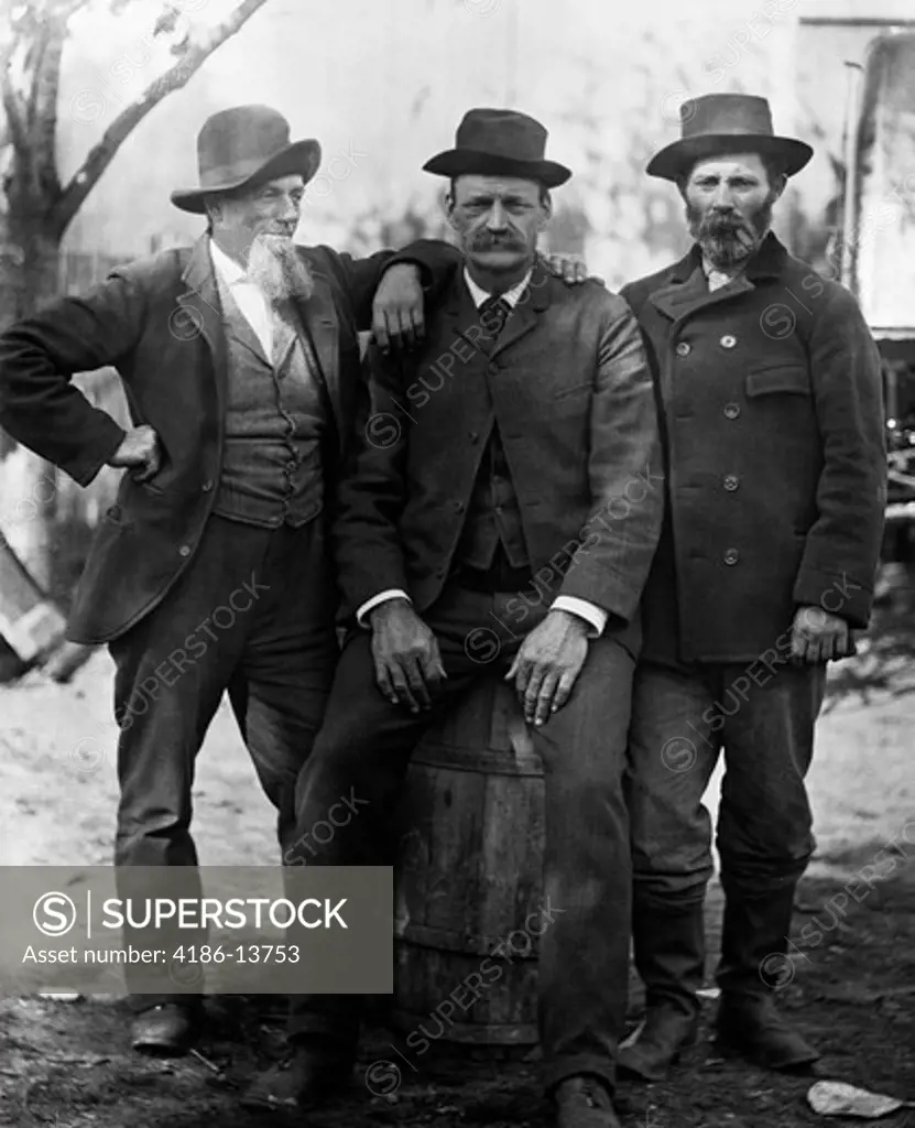 1890S Turn Of The Century Group Of Three Men With Beard Or Mustache Wearing Hats One Sitting On Barrel