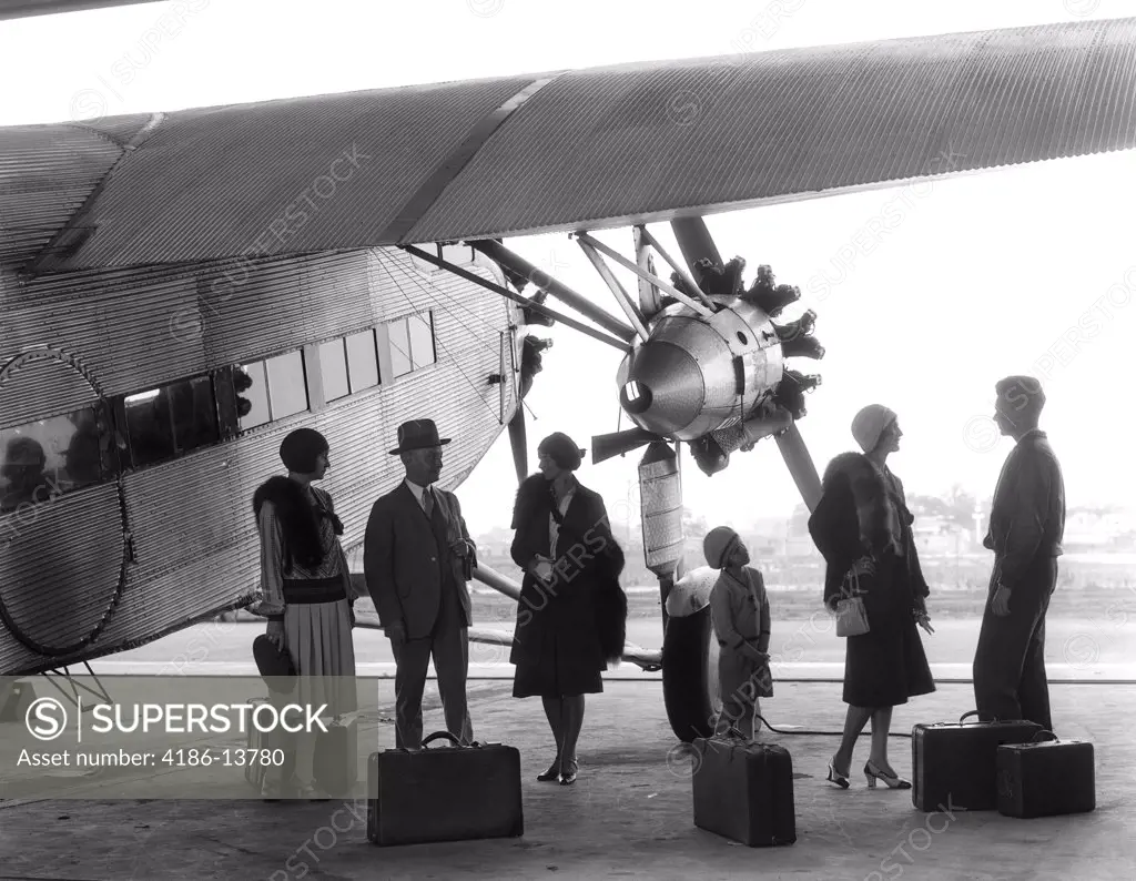 1920S 1930S Group Of Passengers Standing Under Wing Of Ford Tri-Motor Airplane With Baggage