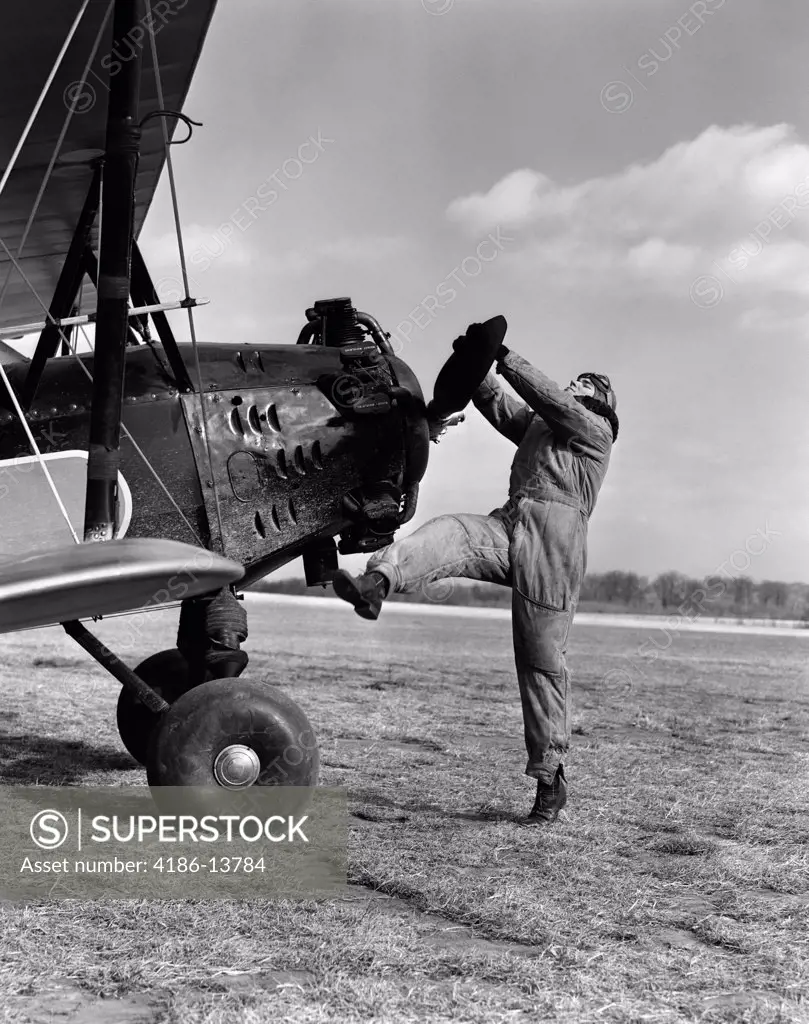 1920S Male Pilot Trying To Turn Plane'S Propeller By Hand