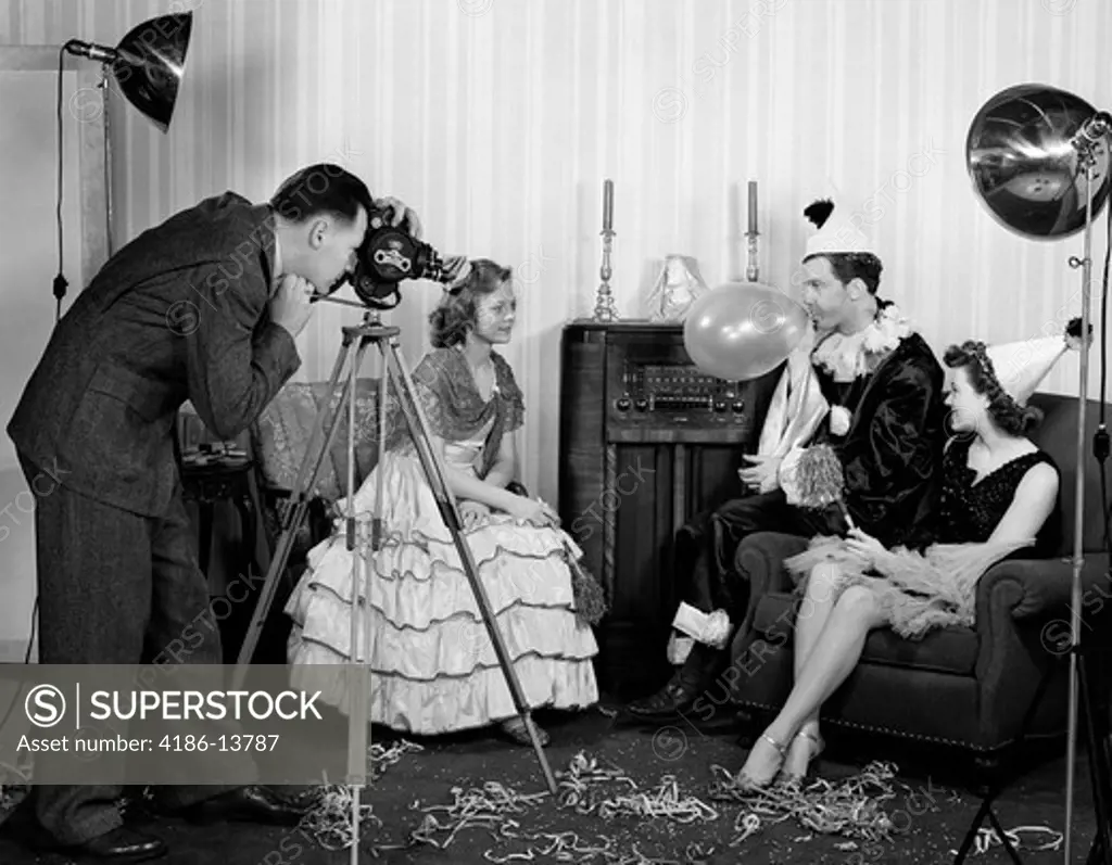 1940S Photographer Taking Picture Of Two Women & A Man Wearing Costumes Man Blowing Up Balloon